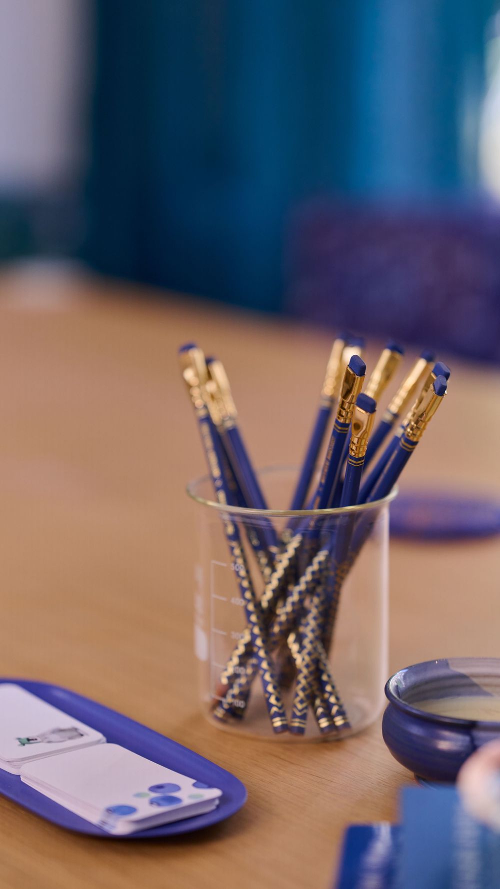 Decorative silver pen holders arranged in a row on a wooden desk with blue accents.