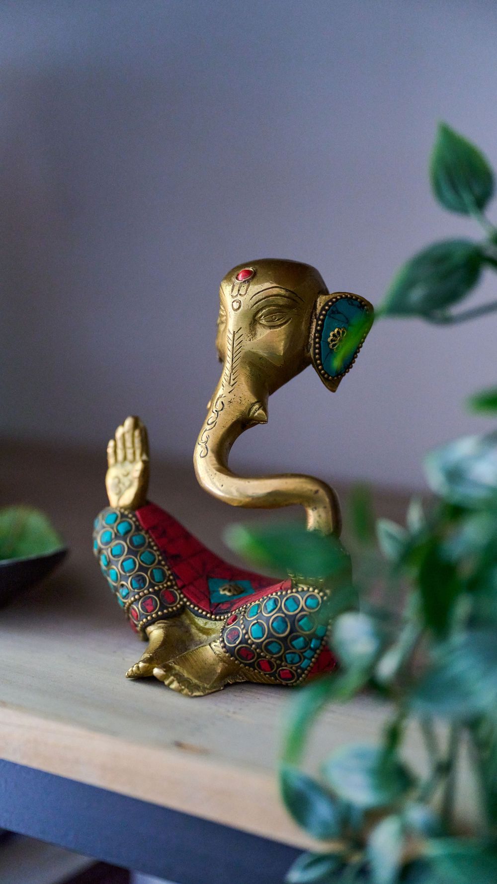 Small gold and turquoise decorative duck figurine photographed from different angles with green foliage in the background.