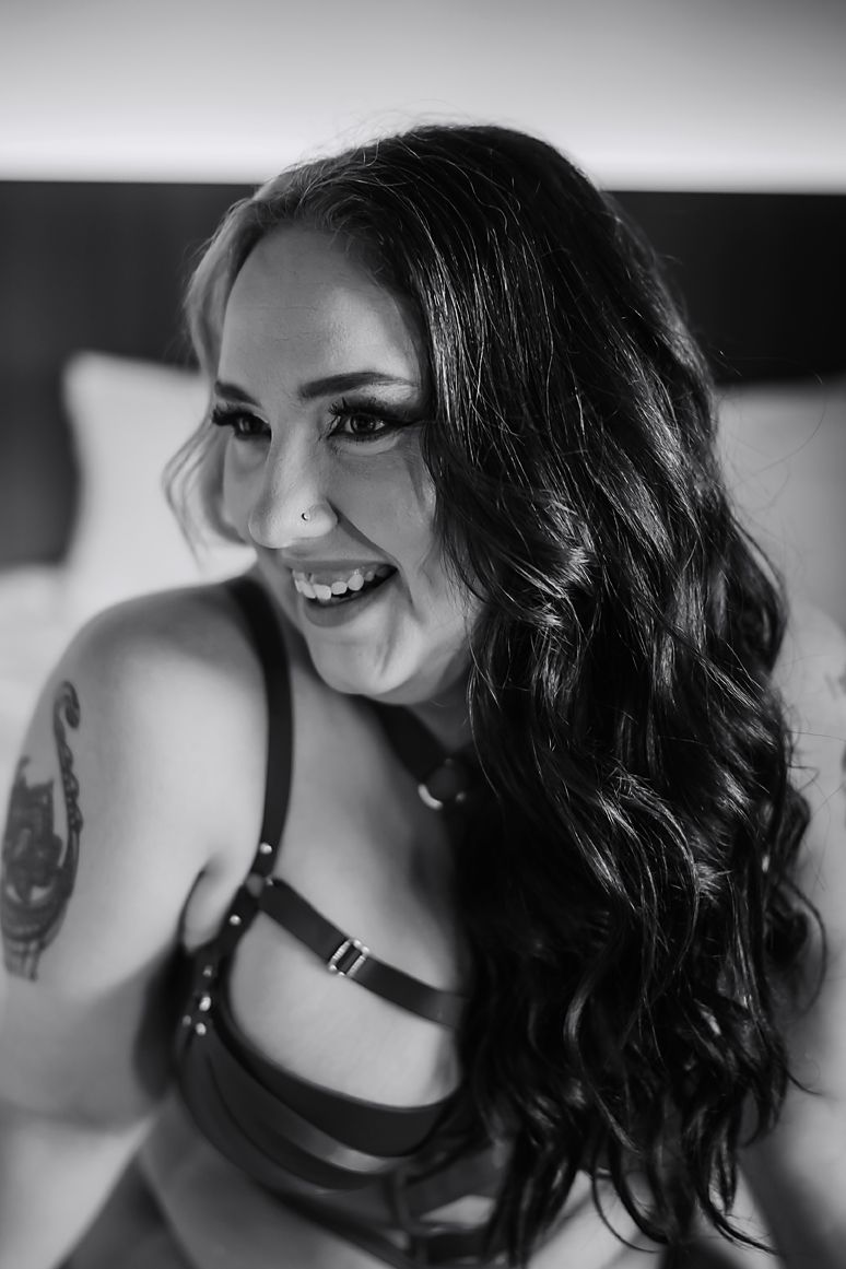 A black and white portrait series showing curly dark hair, nose piercing and a leather harness accessory.