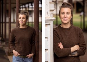 Portrait of someone wearing a brown sweater and jeans posing casually outdoors against architectural details.