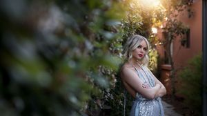 Canberra Model Lorna Munro standing with her arms crossed in a silver gown beside a green hedge at sunset in Canberra.