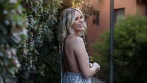 Canberra Model Lorna Munro laughing standing with her arms crossed in a silver gown beside a green hedge at sunset in Canberra.