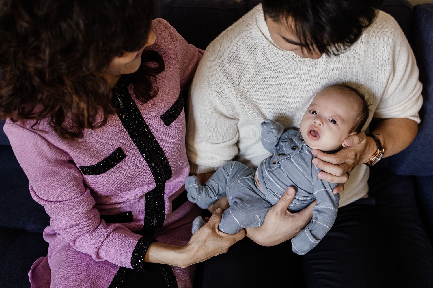 Baby is cuddled by his dad and grandma as his newborn photoshoot in the Bay Area