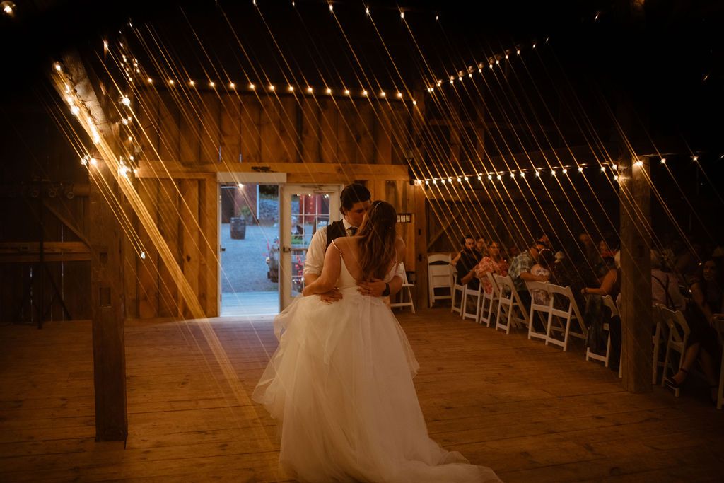 A rustic red barn serves as backdrop for a romantic moment on a wooden deck surrounded by planter boxes.