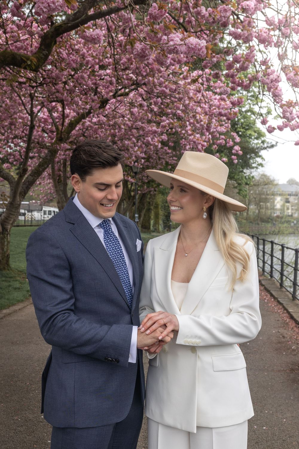 Couple shares loving moment under blooming pink cherry blossom trees in springtime.