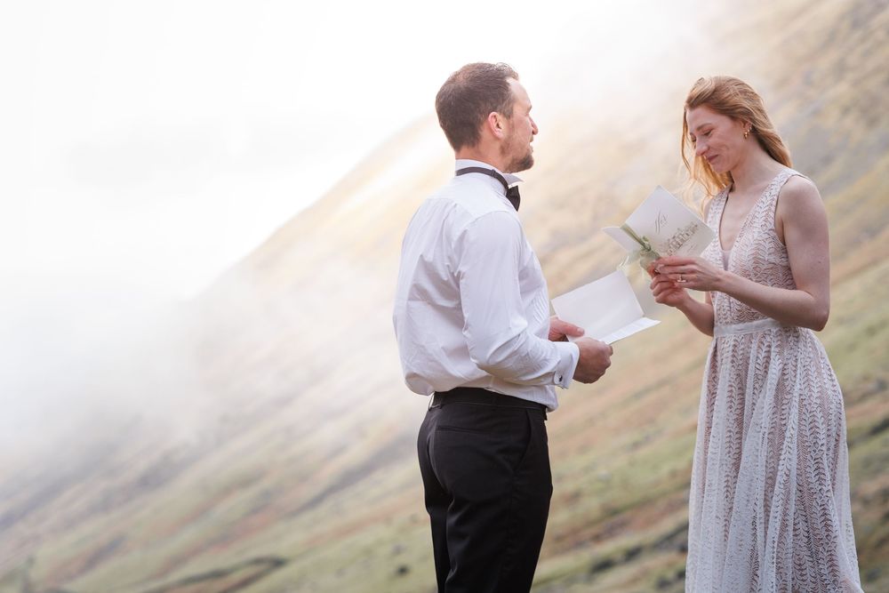 A romantic proposal scene between a couple with mountain ranges in the background at sunset.