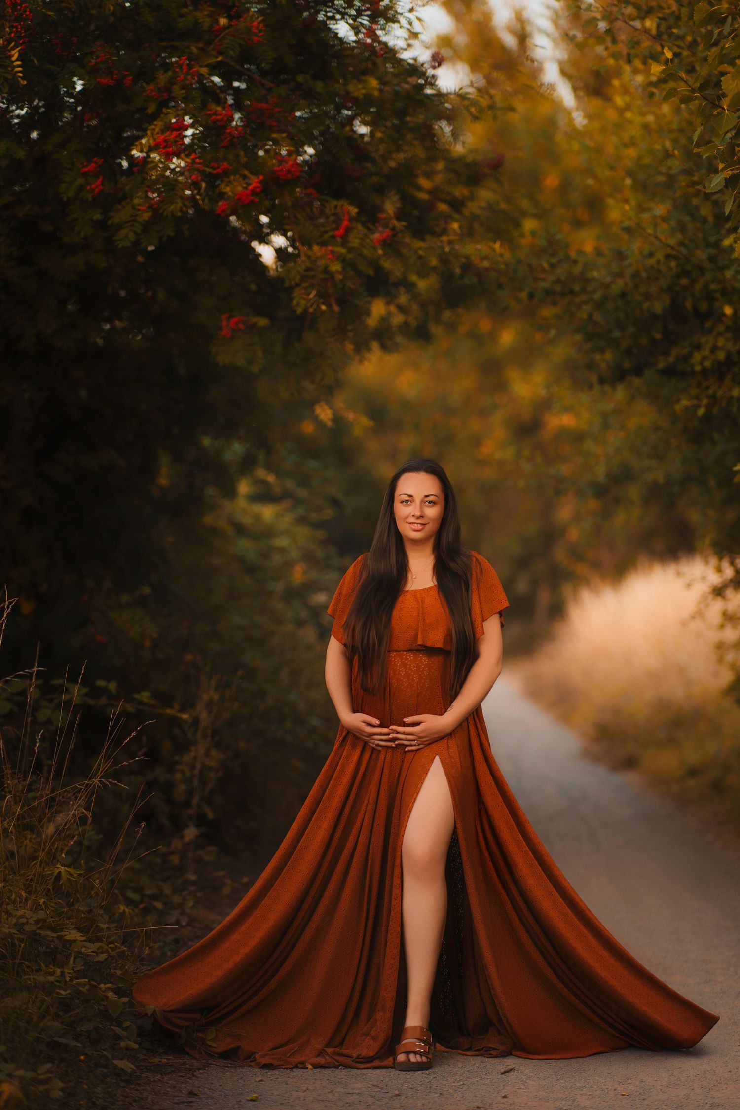 A flowing rust-colored dress dramatically billows along a misty autumn path surrounded by golden trees and foliage.