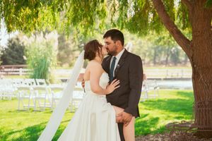 A couple shares intimate moments under a willow tree during their outdoor wedding ceremony.