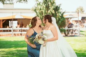 Wedding party poses casually outside on green lawn with willow tree branches hanging overhead.