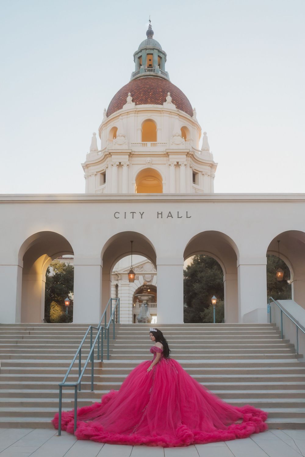 A flowing hot pink formal gown creates a dramatic silhouette against Pasadena City Hall's ornate Spanish Colonial architecture.