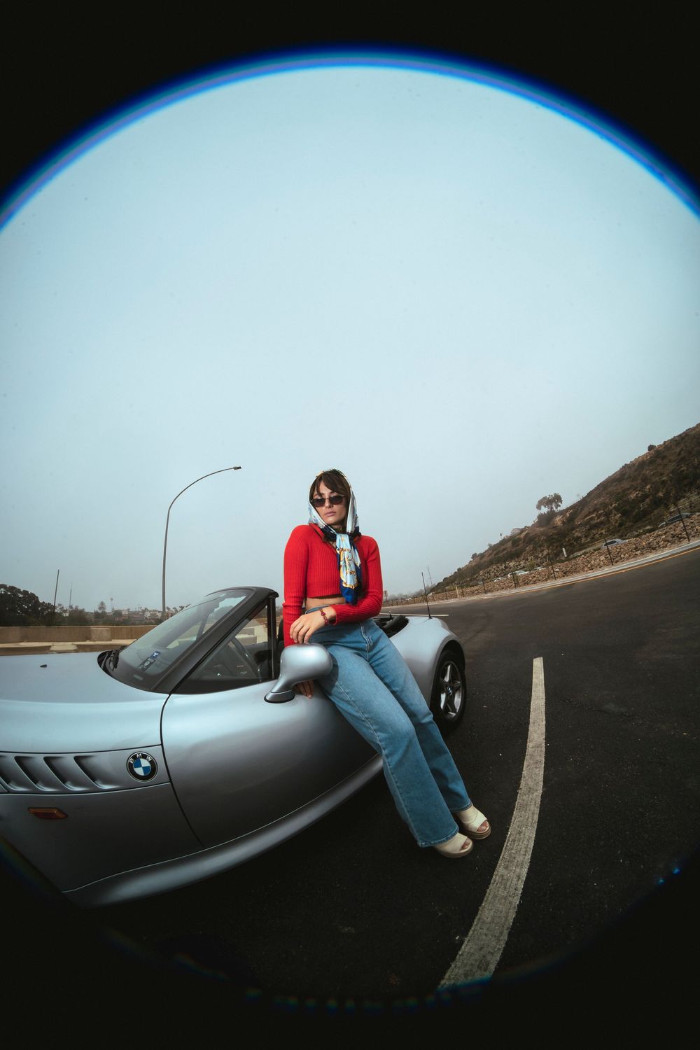 A model poses on a old school BMW with a bright red shirt on