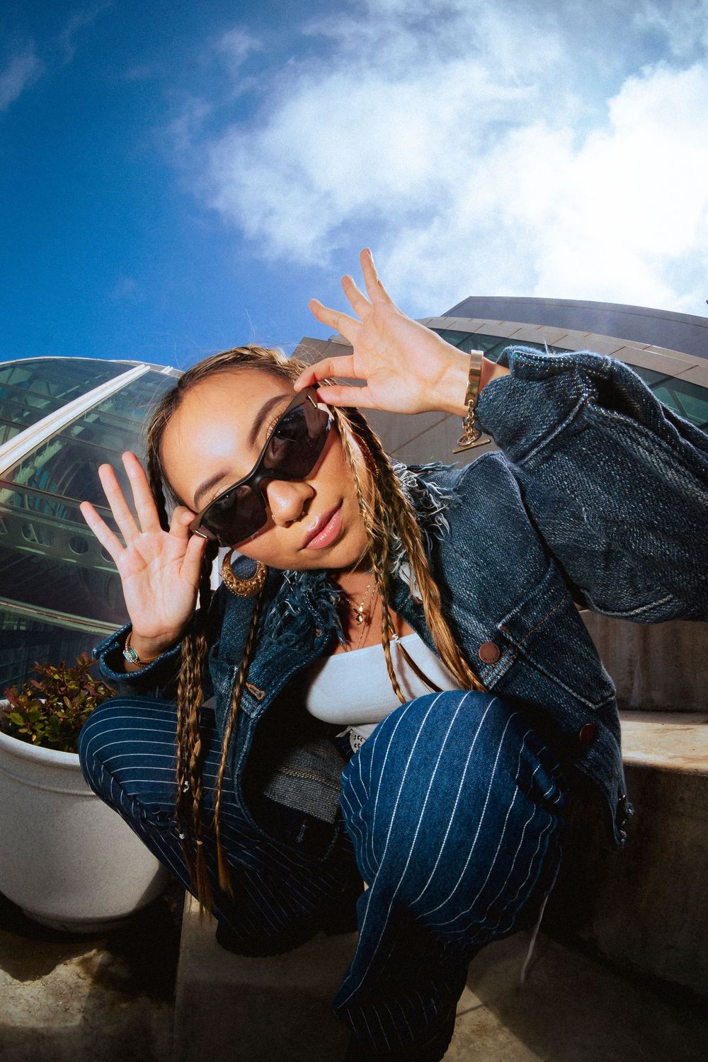 A female model poses holding her sunglasses looking straight at the camera