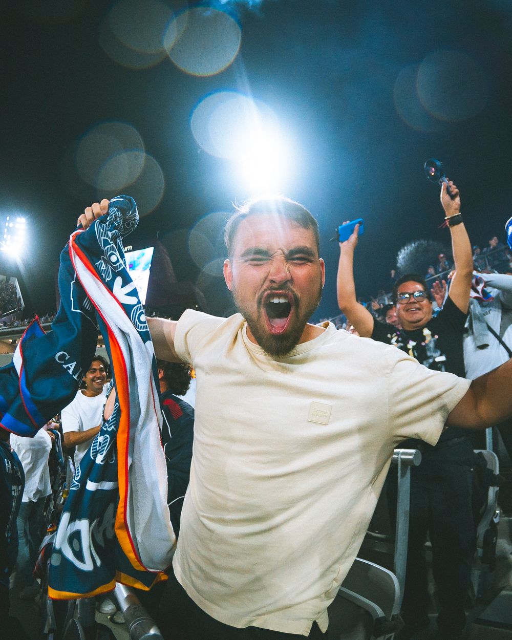 A fan cheers at a soccer game, holding onto a towel