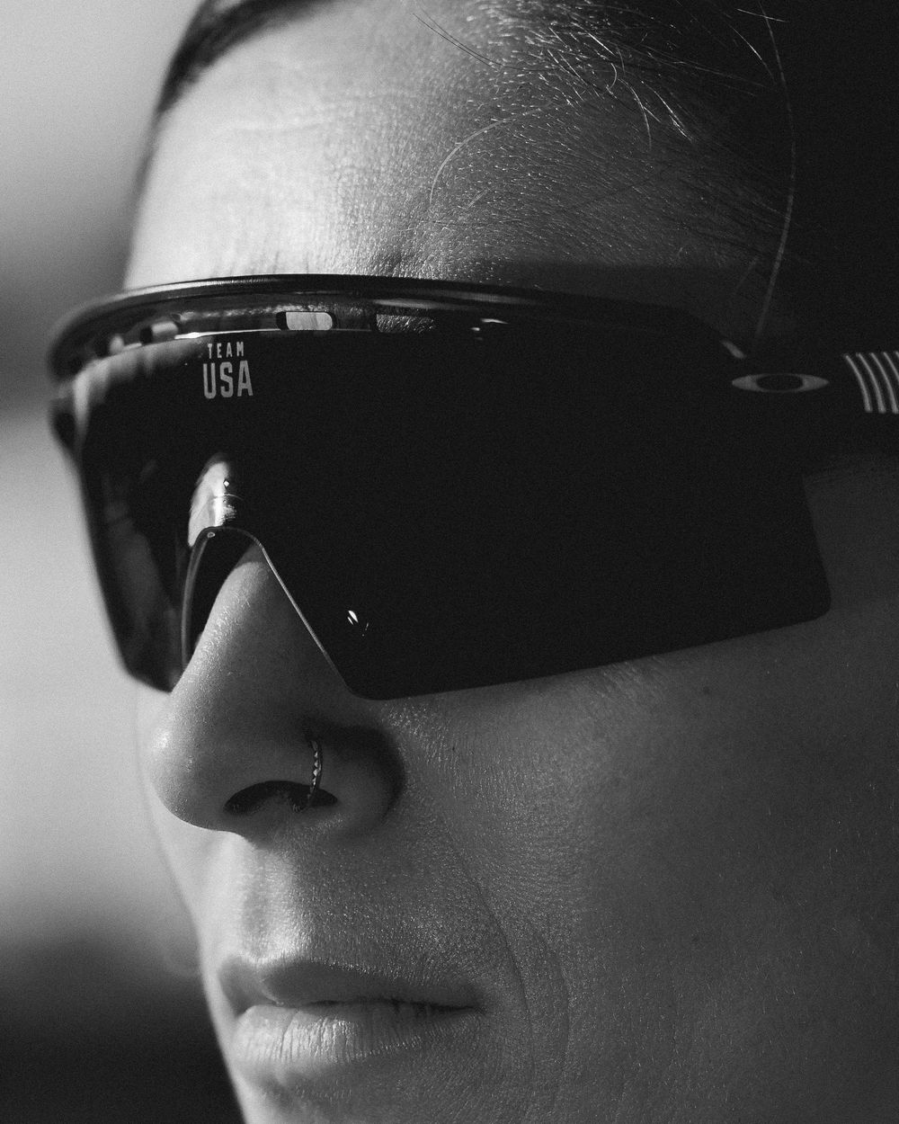 A female model wears sunglasses in a black and white photo