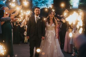 A wedding couple dances under romantic sparkler lighting surrounded by guests at an evening outdoor celebration.