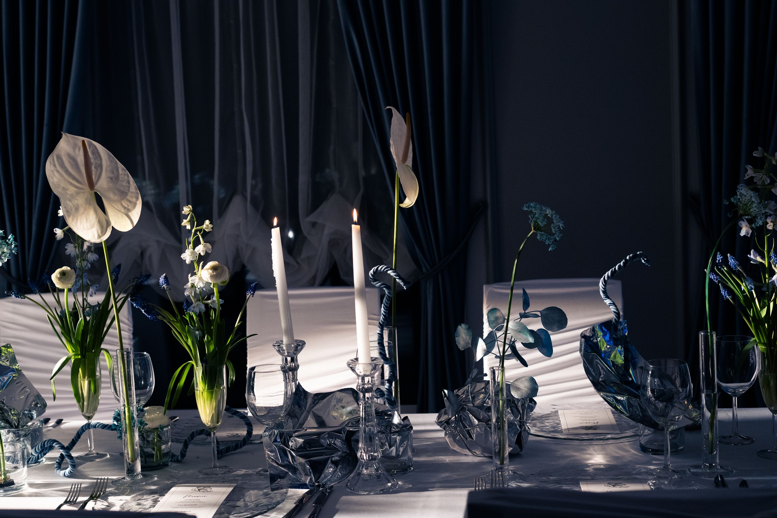 Three identical abstract stylized head sculptures in dark lighting with spotlights creating dramatic shadows and reflections.