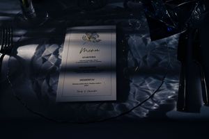 A series of elegant wedding invitations with beautiful calligraphy and decorative elements displayed in dim lighting.