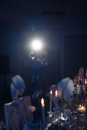 Elegant wedding reception decor at dusk with glowing candles and dramatic lighting creating a romantic atmosphere.