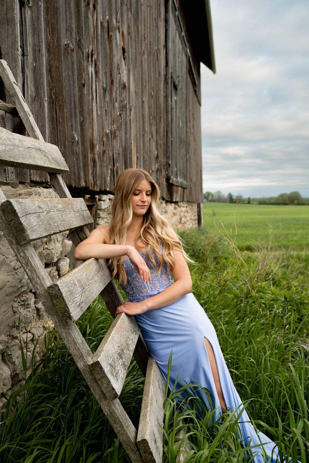 A rustic barn door serves as a backdrop for a romantic outdoor photo shoot in a grassy field.
