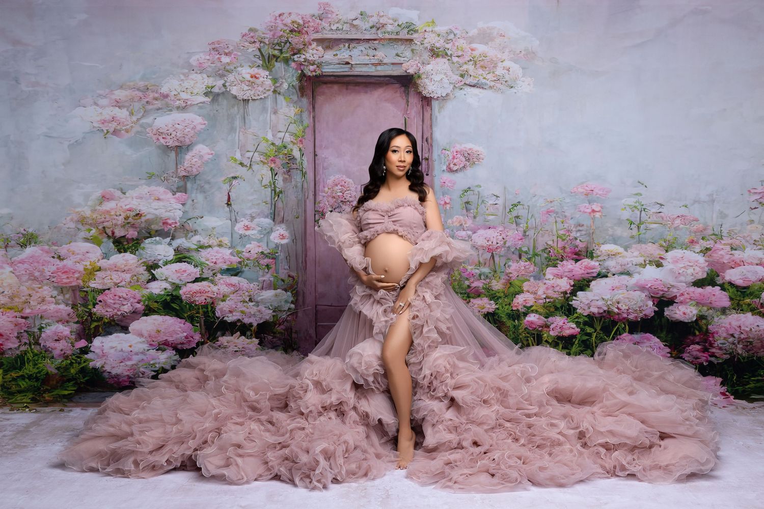 A figure in a romantic pink tulle gown poses gracefully among blooming cherry blossoms in a spring garden photoshoot.