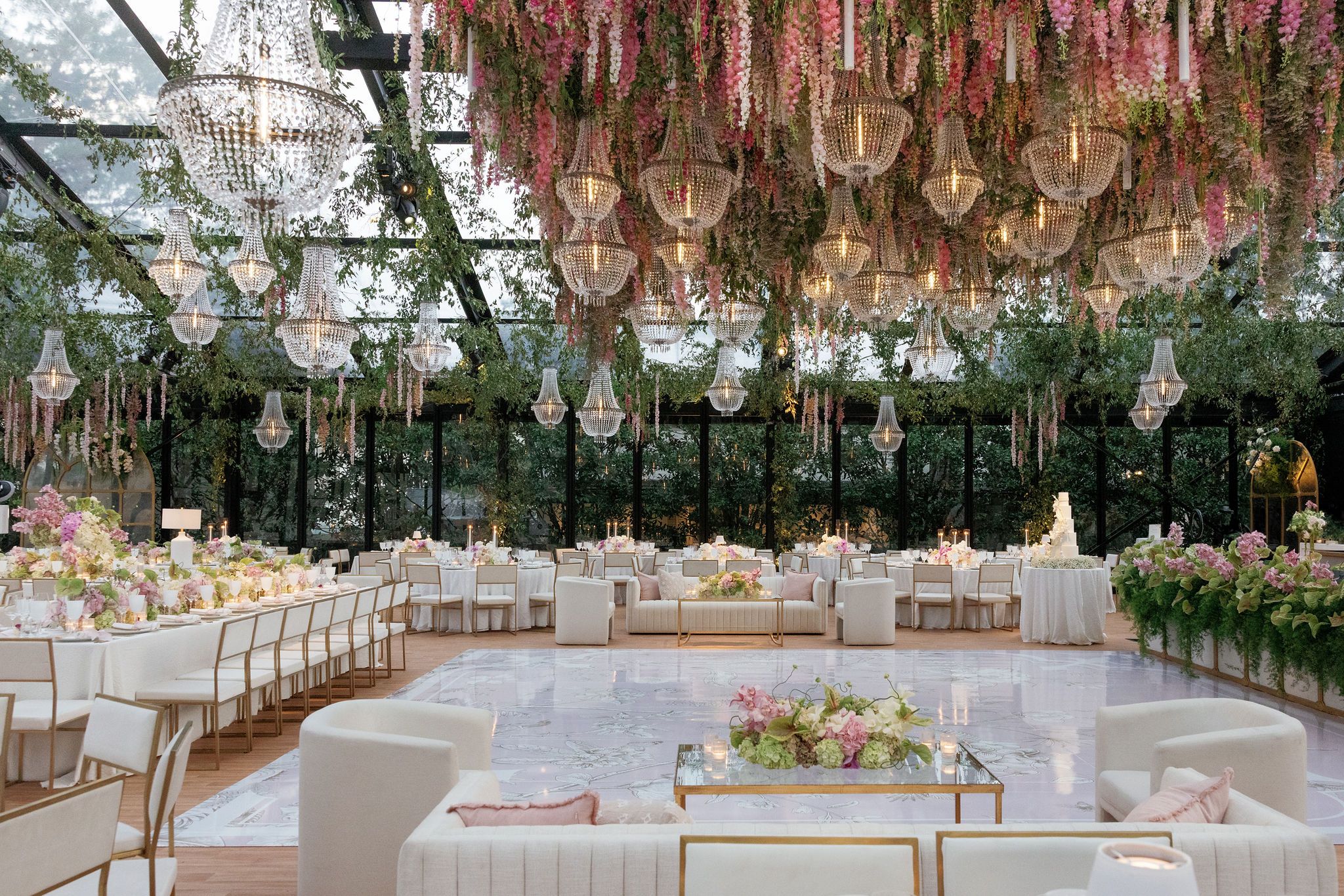 Elegant wedding reception venue with hanging pink wisteria and crystal chandeliers creating a romantic atmosphere.