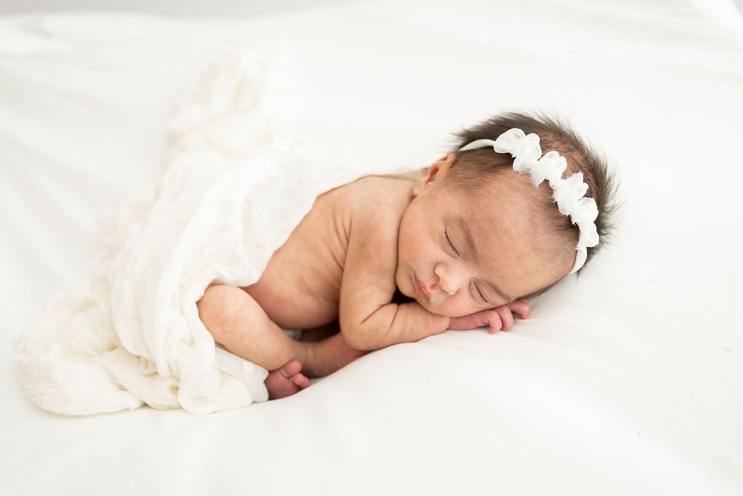 Baby in white outfit crawls on floor with blue and white balloon decorations in bright modern room.