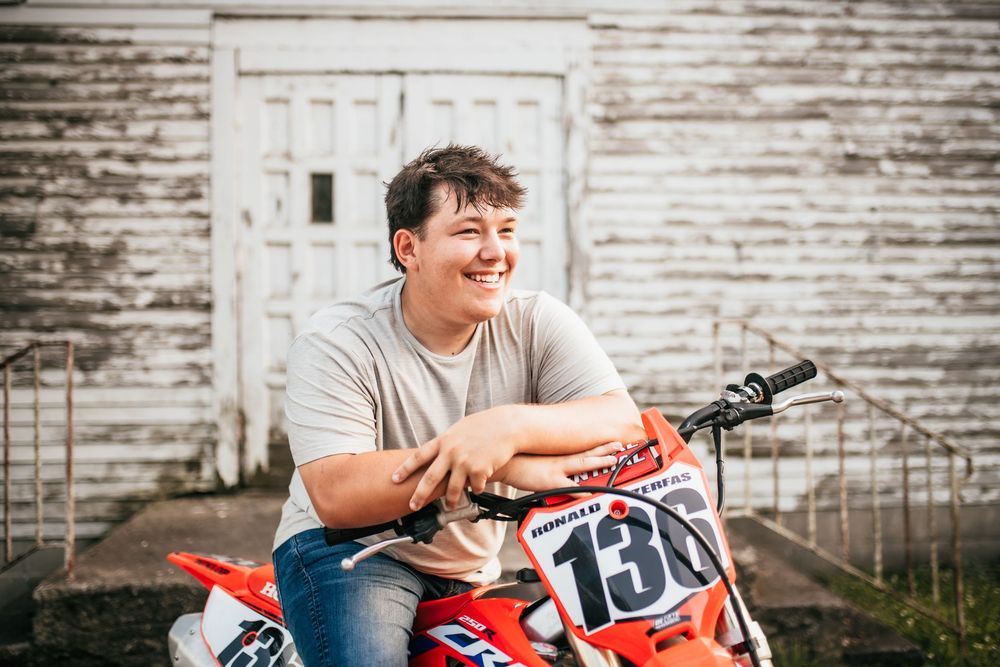 Senior boy smiling on dirtbike with old white country church in the background
