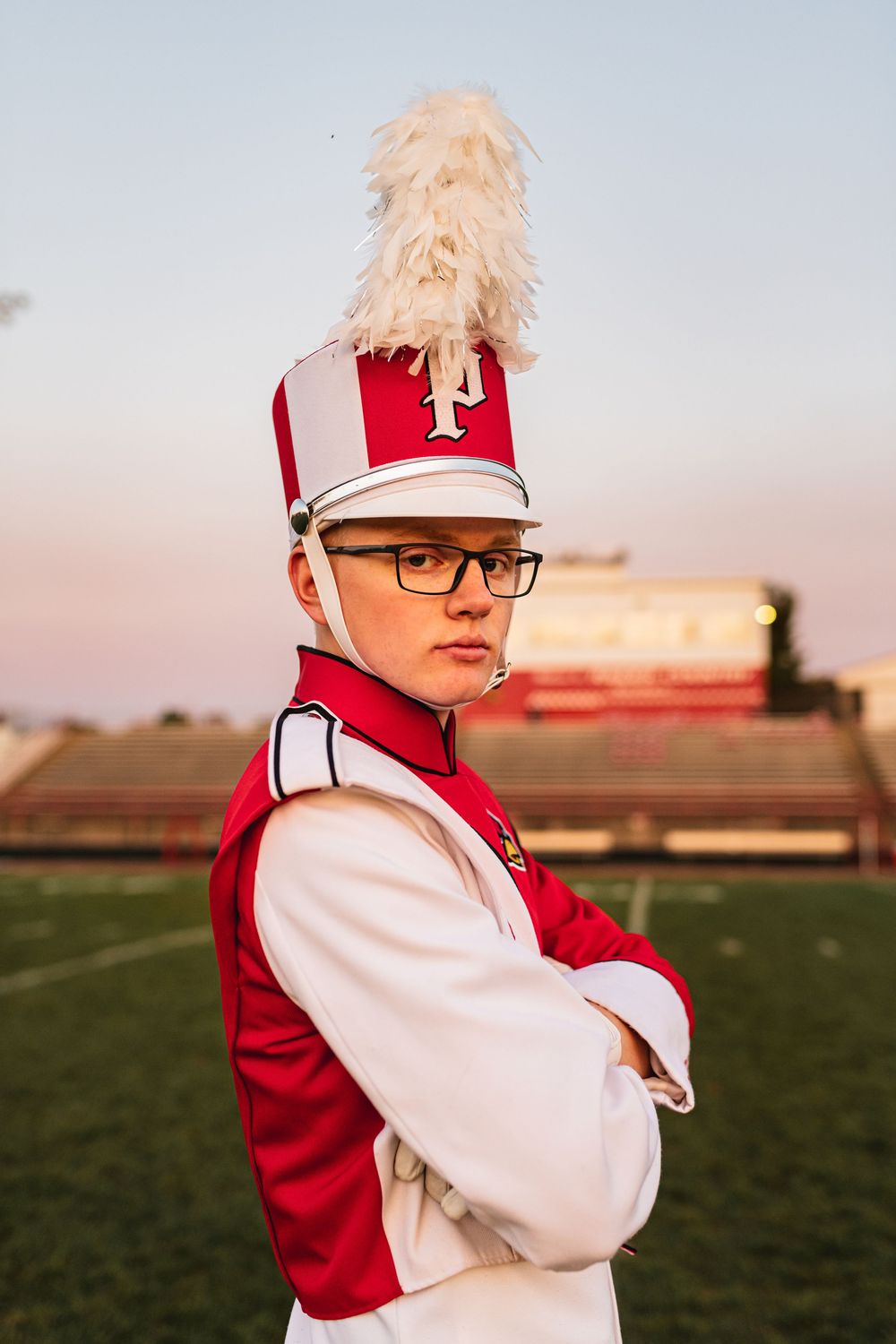 Senior drum major posing in uniform on football field for band-themed senior portrait