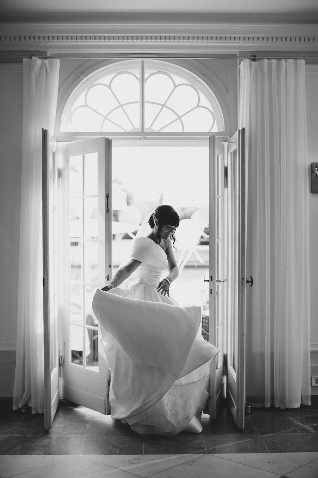 A sequence of elegant black and white photos showing a bride twirling in her wedding dress against a bright window backdrop.
