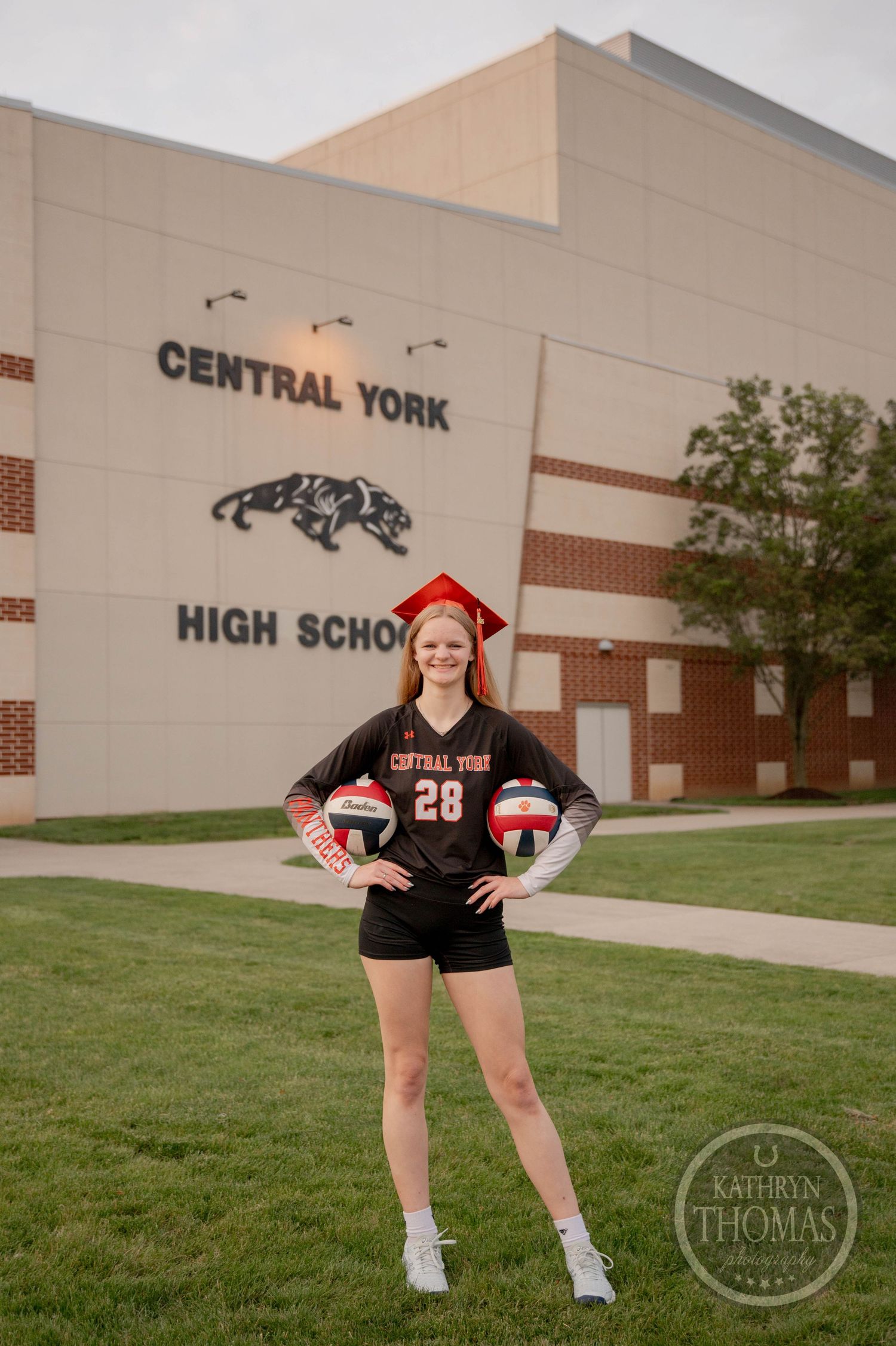 A volleyball player poses outside Central York High School in graduation cap and athletic uniform.