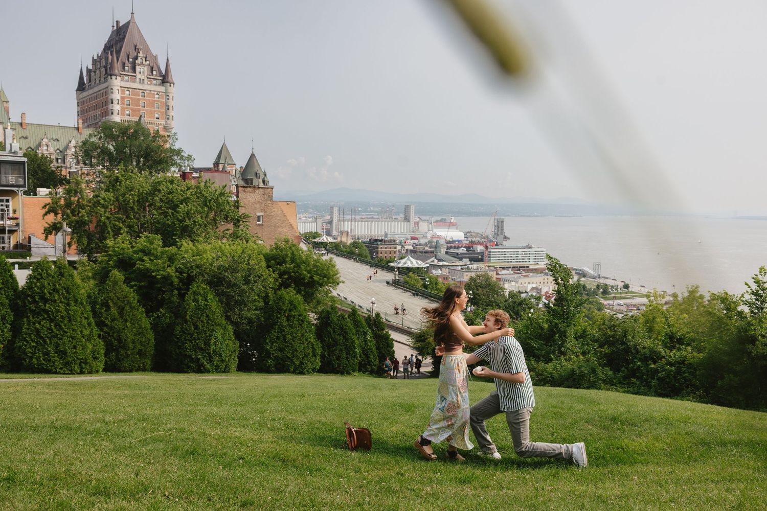 Couple embracing on a hilltop overlooking Quebec City's iconic Chateau Frontenac and historic skyline during sunset.