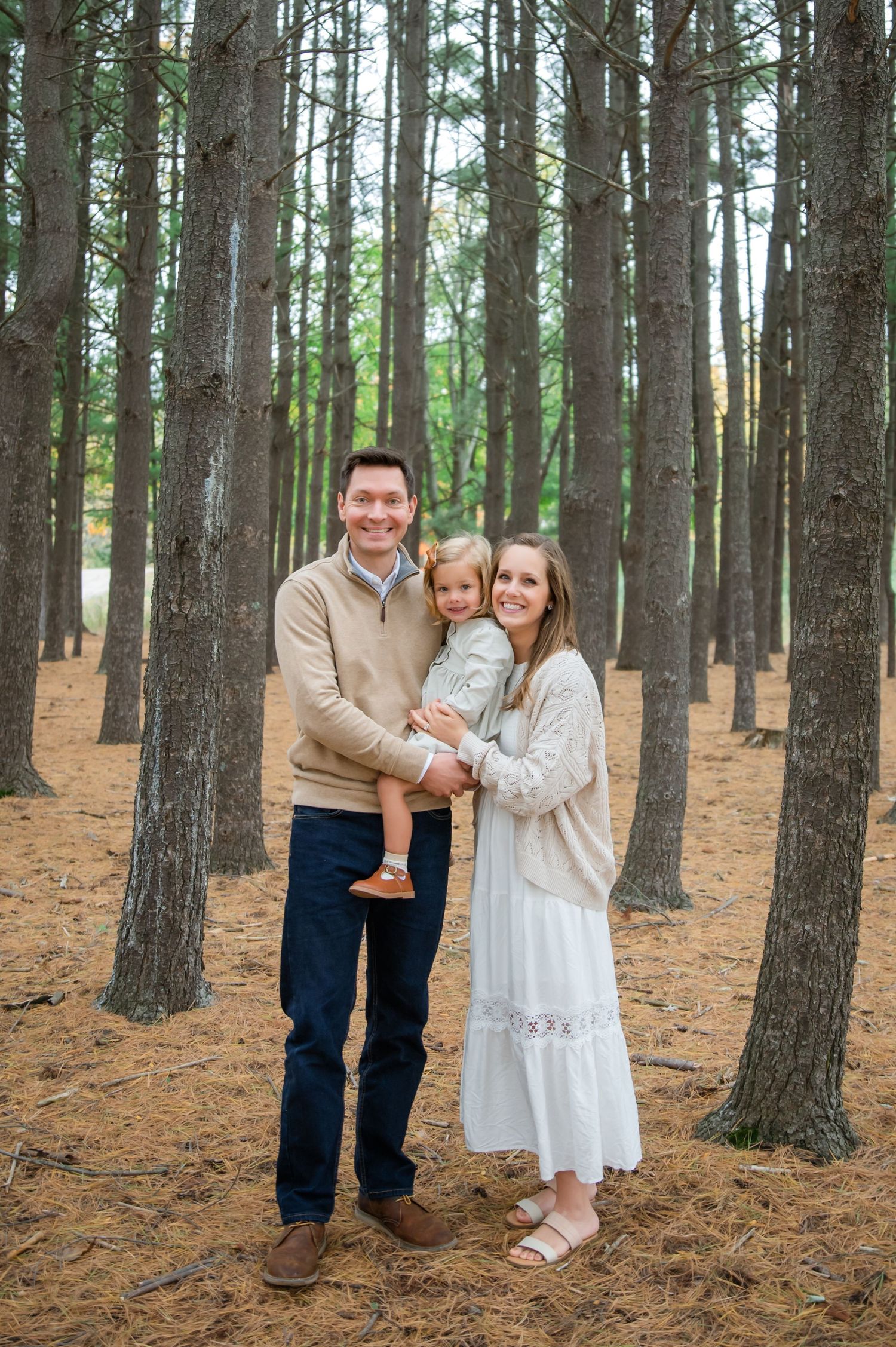 Candid family photos captured in a serene pine forest with natural lighting and white clothing.