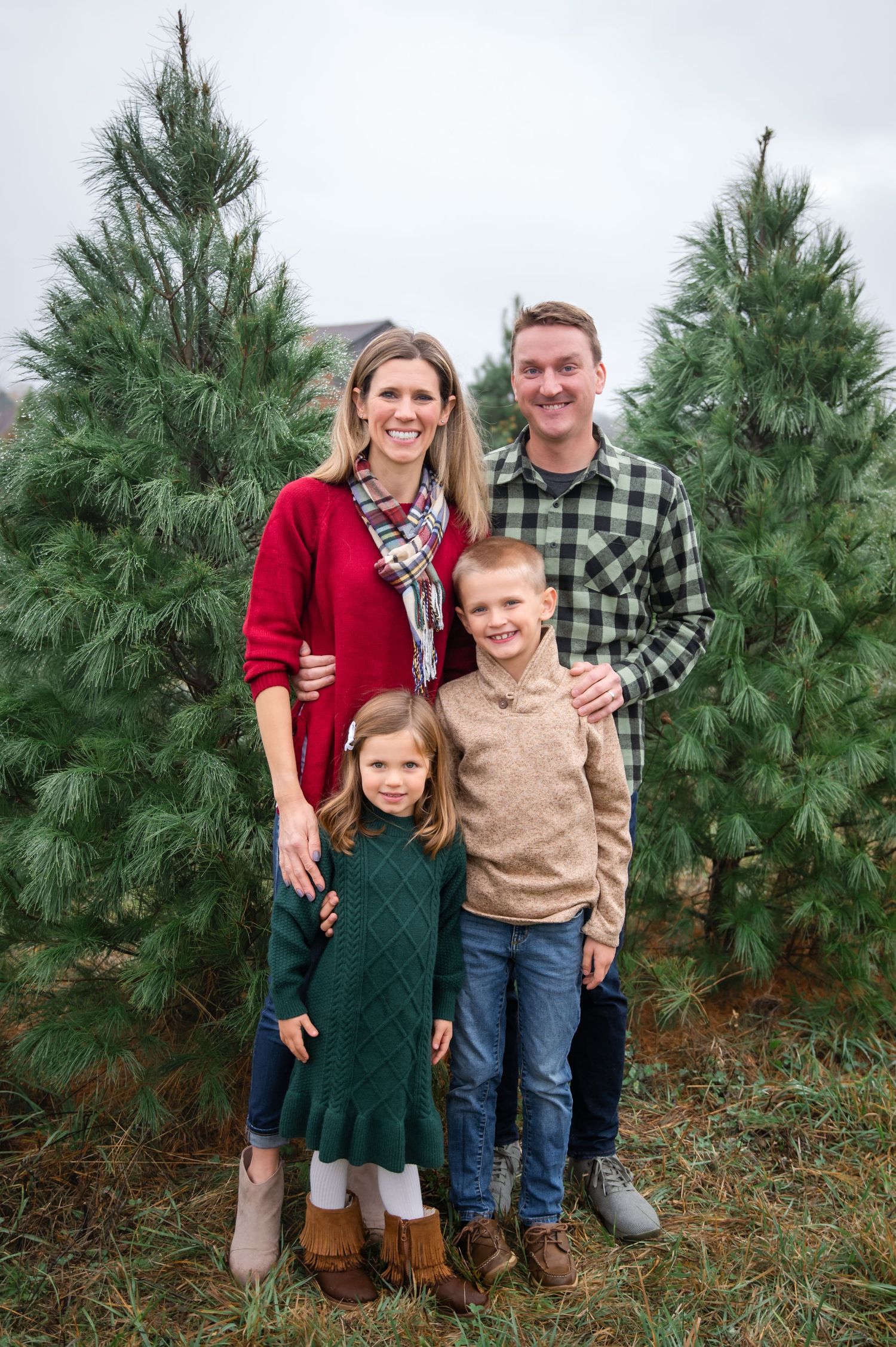 A family portrait in a room with brick walls and teal trim, sitting on and around a sage green velvet couch.