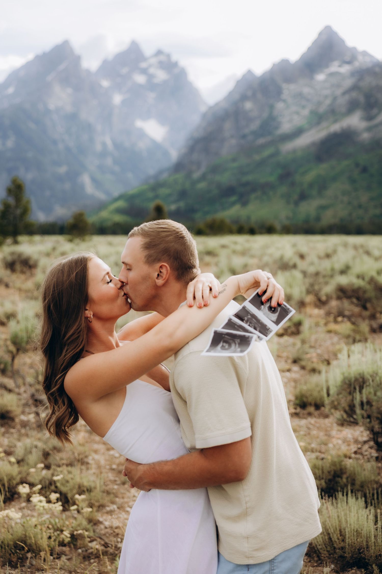 A romantic couple shares intimate kisses against the stunning backdrop of the Grand Teton mountains in Wyoming.