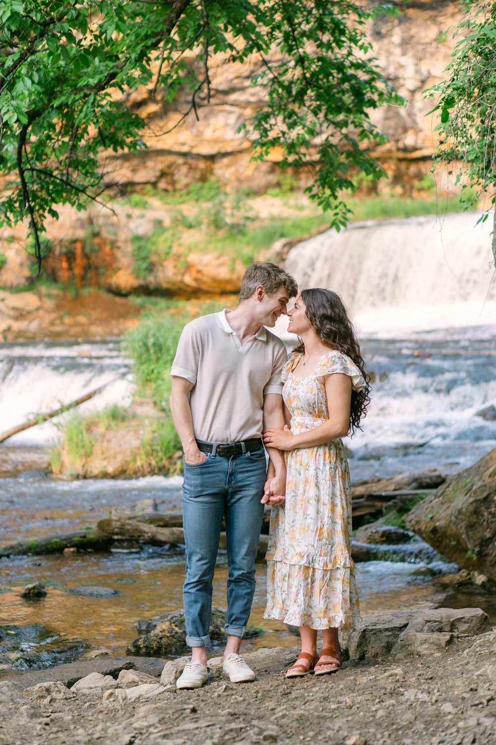 Bride-to-be in a flowy dress gazing at her fiancé during a golden hour engagement session at Willow River State Park