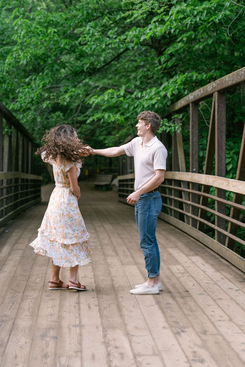 Couple dancing on a wooden bridge with lush green trees behind them at Willow River State Park