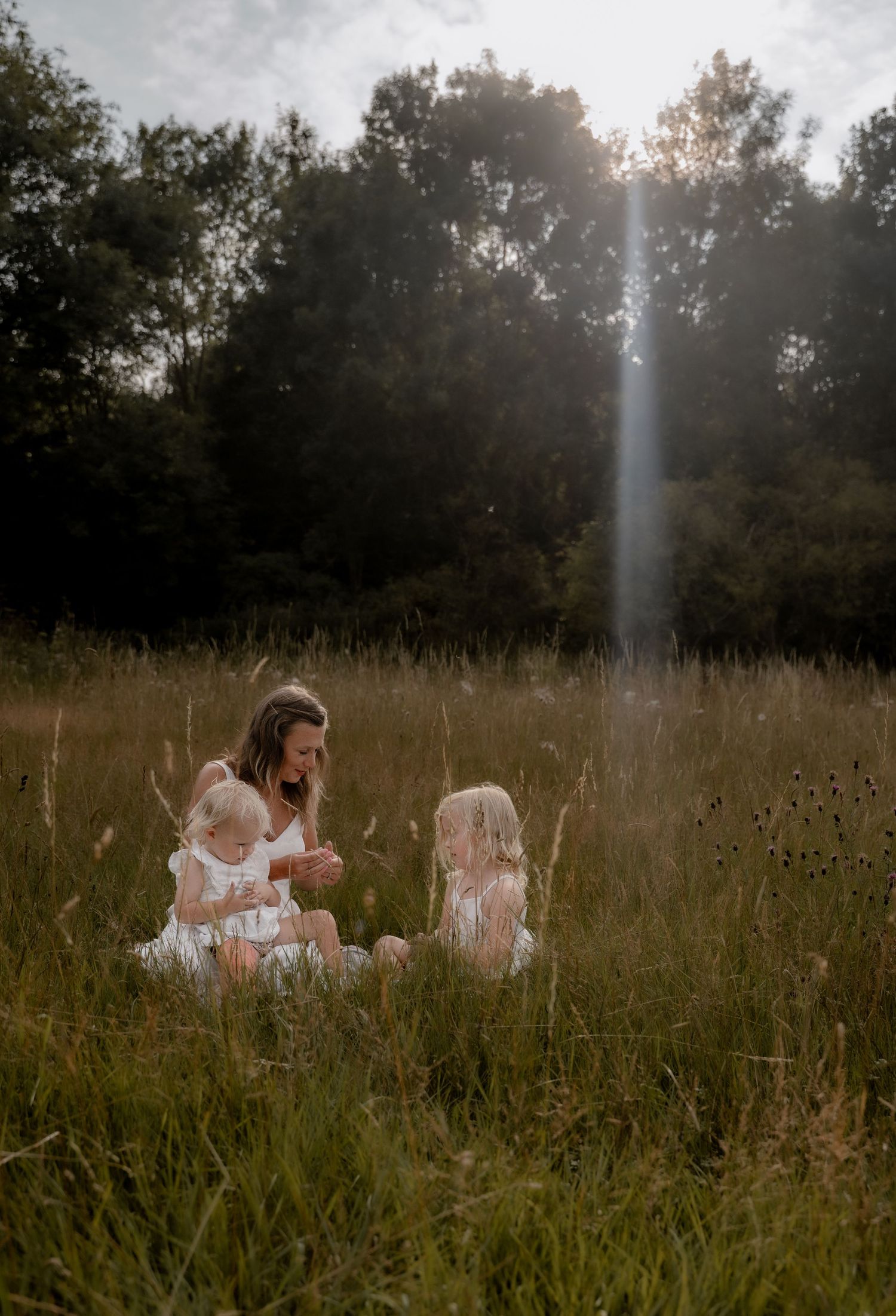 Mother and child chasing bubbles in a golden meadow during a Derbyshire lifestyle photography session.