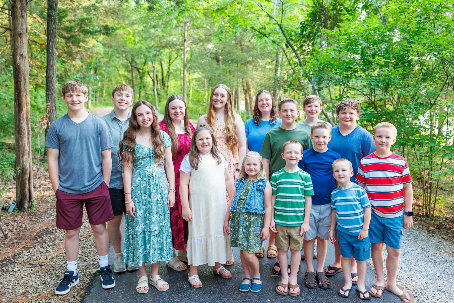 Group of children standing together outdoors on a gravel path surrounded by green trees and foliage in Branson, Missouri.