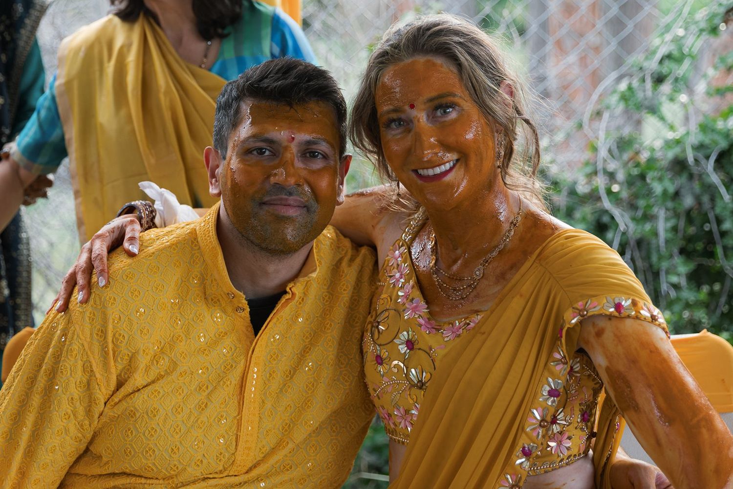 Couple smiling together covered in turmeric paste after traditional Indian haldi wedding ceremony.