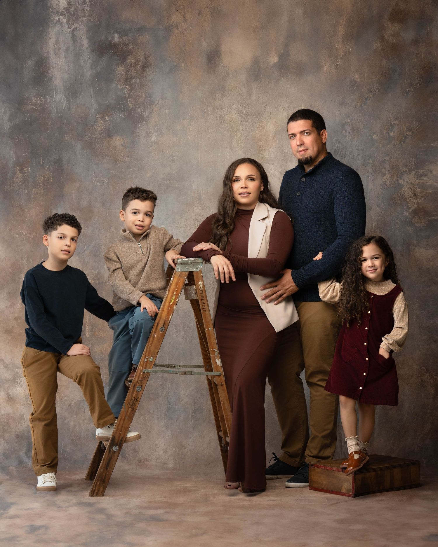 A series of five studio portraits showing playful family poses with brown and neutral tones against a textured backdrop.