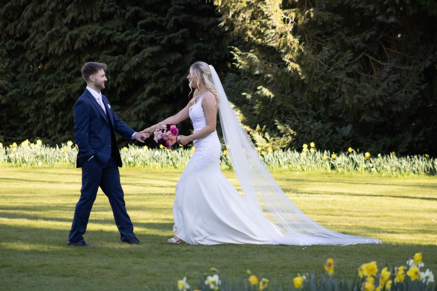 Bride and groom walking across lawn at Oxfordshire wedding venue
