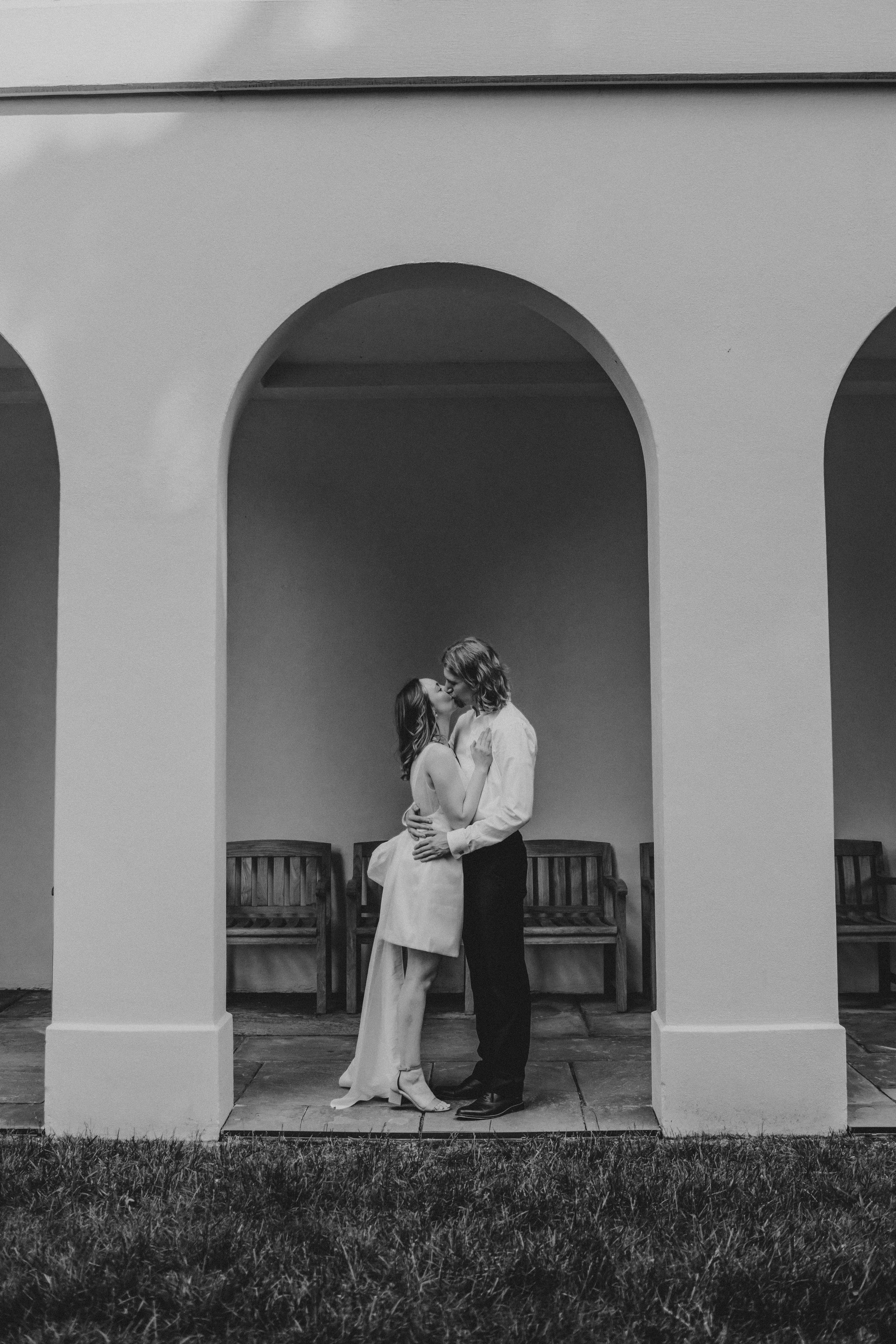 Elegant black and white photos show a couple's romantic moments beneath arched white columns.