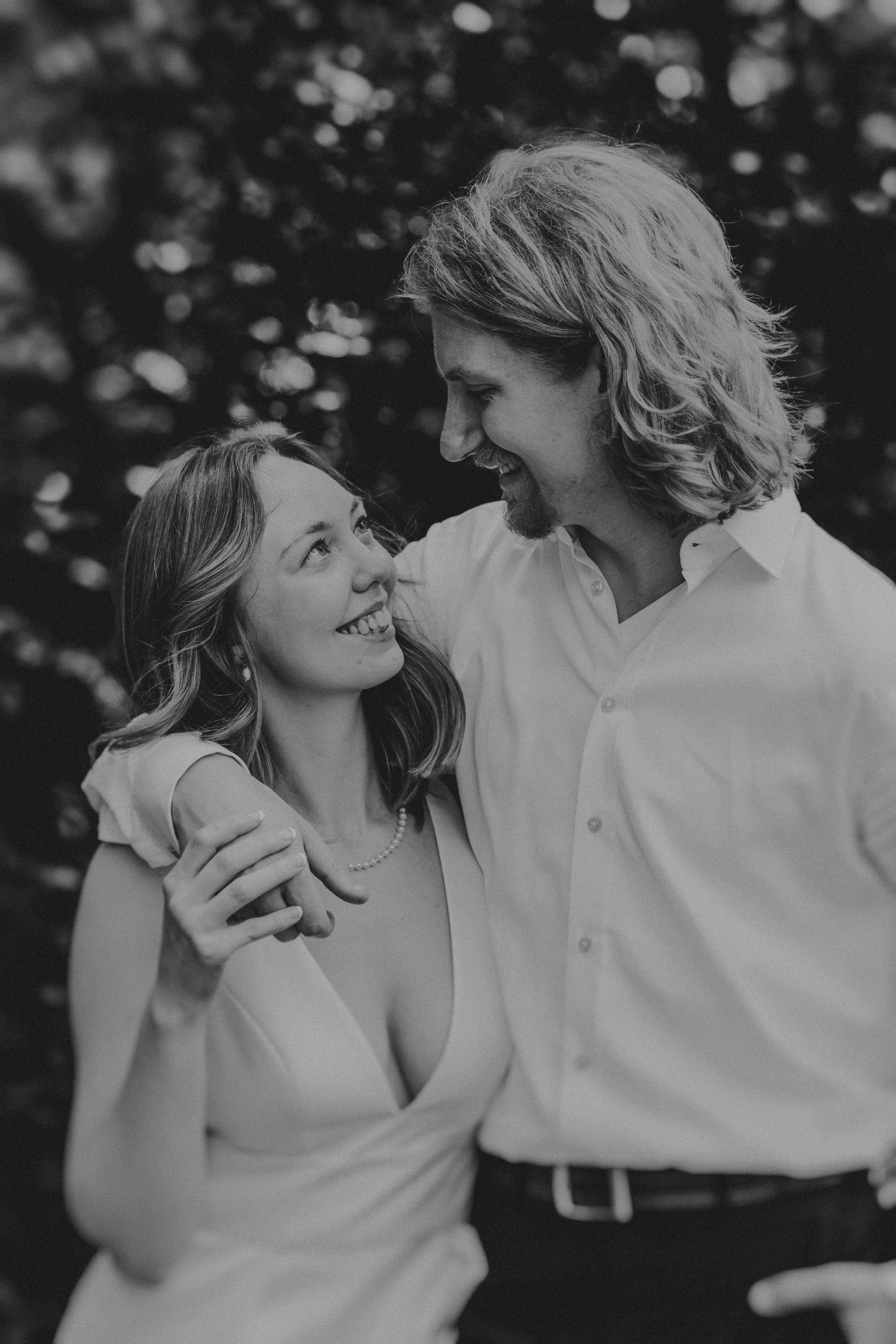 Black and white photo series capturing a couple sharing intimate laughing moments outdoors.