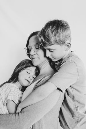 Black and white portrait of a mother embracing her two children in a tender family hug.