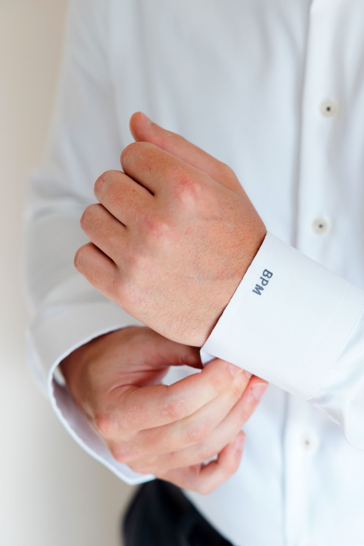 Groom adjusting cuffs.