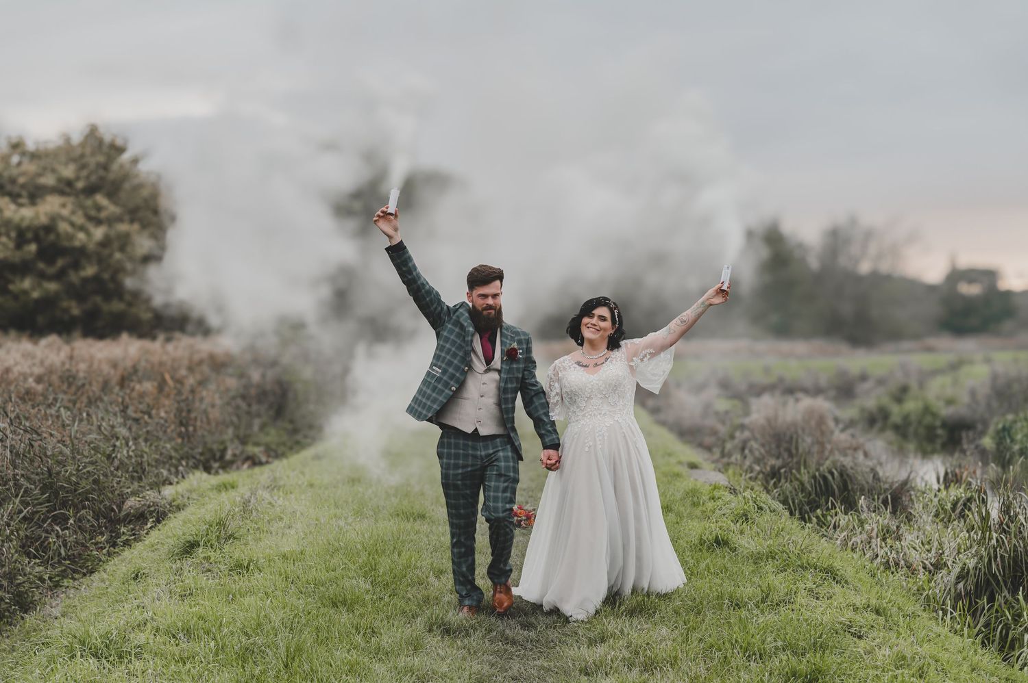 A couple celebrates their wedding day in a misty outdoor setting with rolling hills and natural greenery in the background.