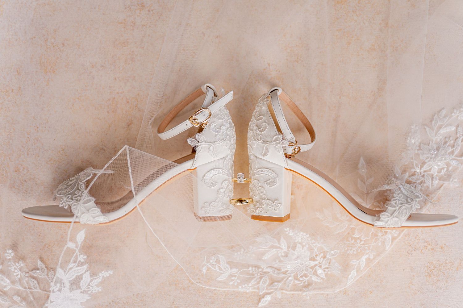 Elegant white wedding shoes arranged in a row on a light beige background.