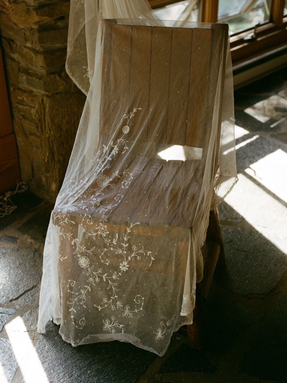 Delicate white lace curtains with intricate floral patterns hang in sunlit windows.
