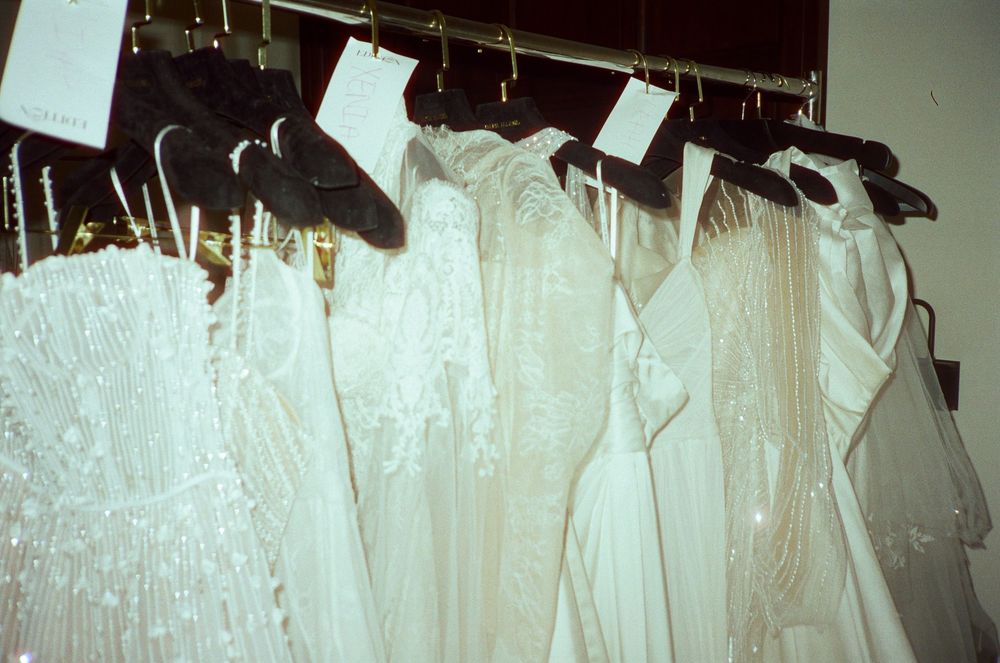 Wedding dresses hanging in a row on display, showing various white gowns with intricate details.