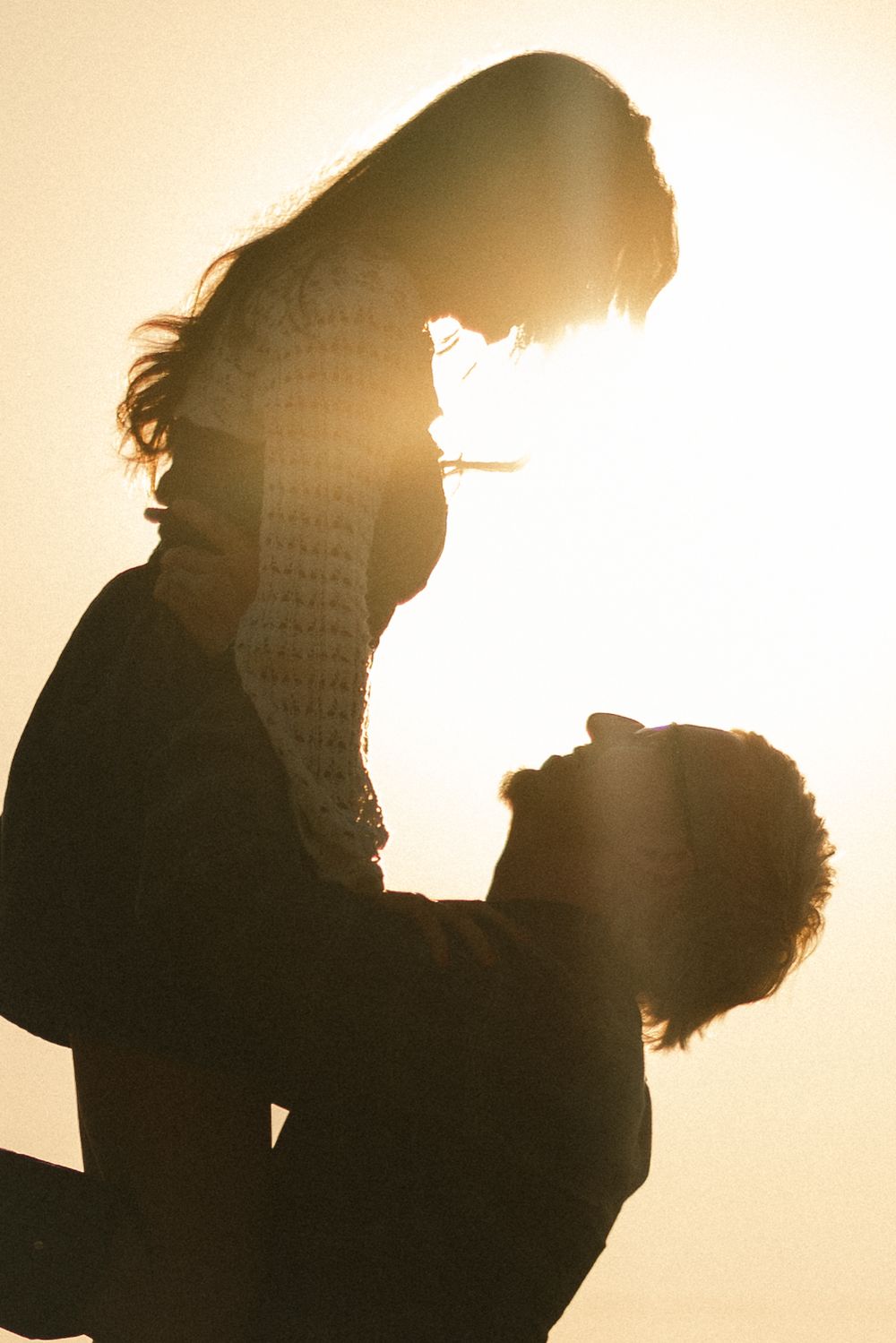 The sun illuminates a couple while they are looking deeply into each other's eyes